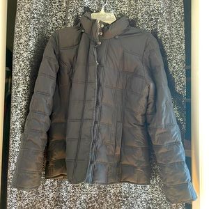 A black puffy coat with two pockets, a zipper, buttons in the front and a hood.